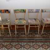 Qui anche le sedie esprimono inventiva: ne notiamo in particolare quattro sulla destra, decorate con la tecnica del decoupage